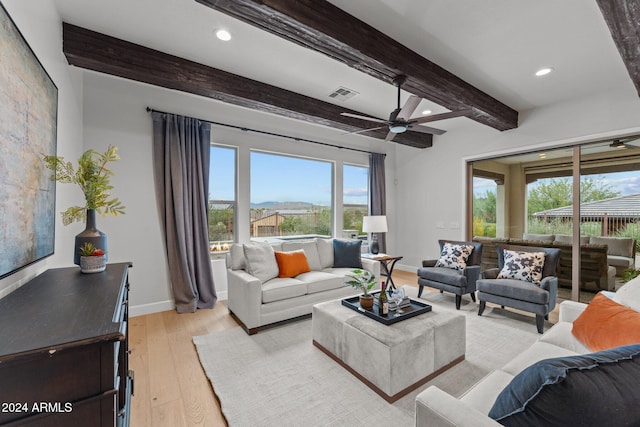 living room featuring beamed ceiling, a mountain view, light hardwood / wood-style floors, and ceiling fan