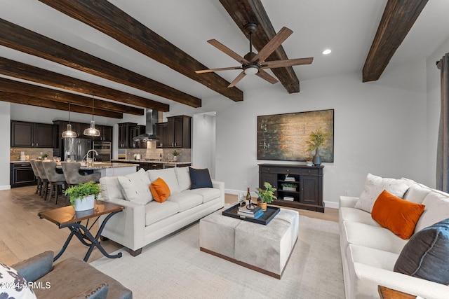 living room with beamed ceiling, light wood-type flooring, and ceiling fan