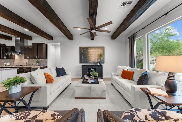 living room with ceiling fan, beamed ceiling, and light hardwood / wood-style floors