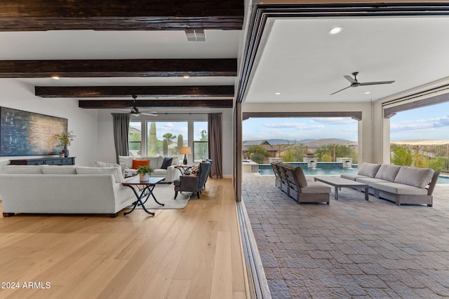 living room featuring light hardwood / wood-style floors, a healthy amount of sunlight, and beamed ceiling