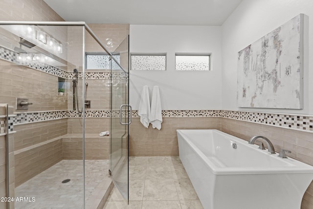 bathroom featuring shower with separate bathtub, a healthy amount of sunlight, and tile walls