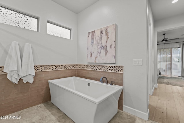 bathroom with a bathtub, ceiling fan, plenty of natural light, and hardwood / wood-style floors