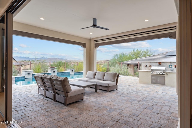 view of patio / terrace with grilling area, exterior kitchen, a mountain view, an outdoor living space, and a fenced in pool