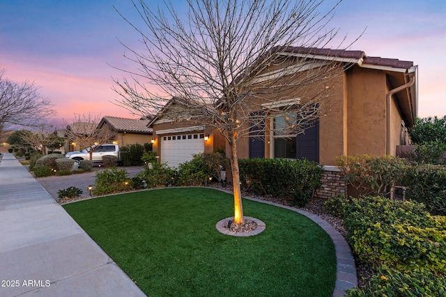 view of front of home with a garage and a lawn