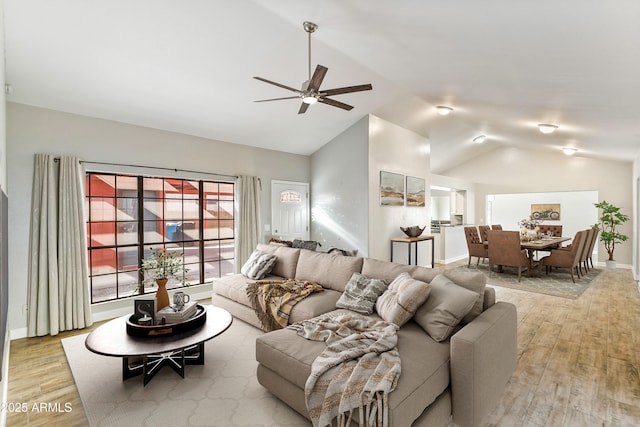 living room with ceiling fan, light wood-type flooring, and vaulted ceiling