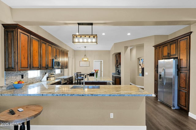 kitchen featuring pendant lighting, sink, a kitchen breakfast bar, stainless steel appliances, and kitchen peninsula