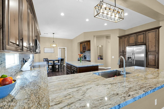 kitchen featuring sink, an inviting chandelier, stainless steel appliances, a kitchen island, and decorative backsplash