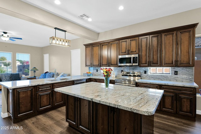 kitchen featuring appliances with stainless steel finishes, pendant lighting, sink, kitchen peninsula, and dark brown cabinets