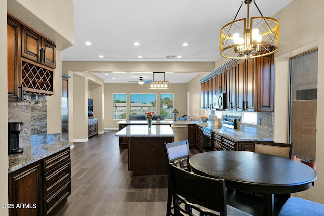 dining area with dark hardwood / wood-style flooring and ceiling fan with notable chandelier