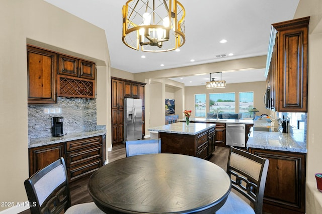 kitchen featuring appliances with stainless steel finishes, a chandelier, hanging light fixtures, a center island, and kitchen peninsula