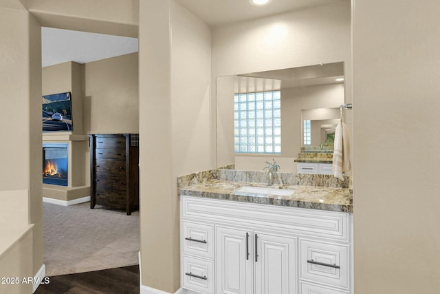 bathroom featuring vanity, hardwood / wood-style floors, and a multi sided fireplace