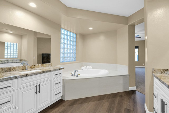 bathroom with hardwood / wood-style flooring, vanity, and a bath