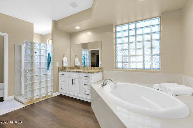 bathroom with vanity, hardwood / wood-style floors, toilet, and a tub to relax in