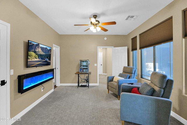 carpeted living room with a fireplace and ceiling fan