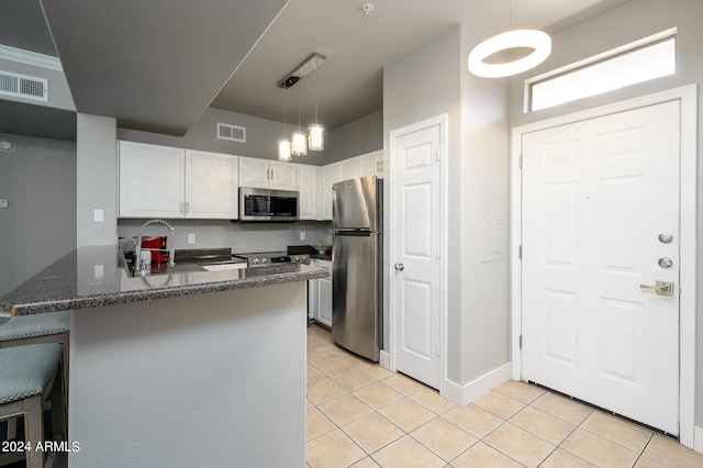 kitchen featuring kitchen peninsula, white cabinetry, stainless steel appliances, and hanging light fixtures