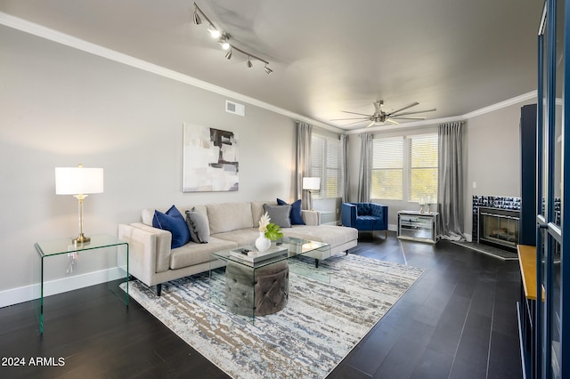 living room with a tile fireplace, ceiling fan, rail lighting, dark hardwood / wood-style floors, and ornamental molding