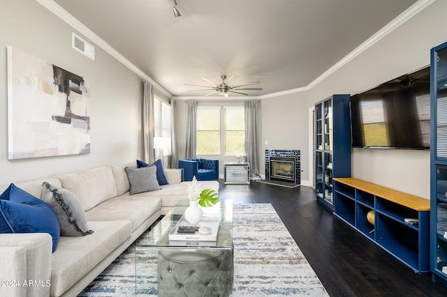 living room with dark hardwood / wood-style floors, ceiling fan, ornamental molding, and a tiled fireplace