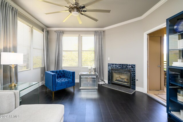 sitting room featuring hardwood / wood-style floors, ceiling fan, crown molding, and a tiled fireplace