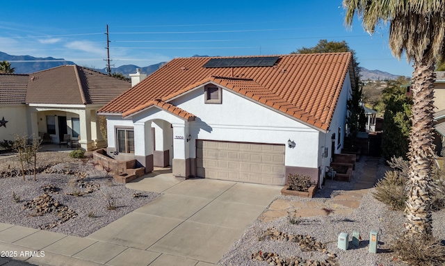 view of front of house with a garage, a mountain view, and solar panels