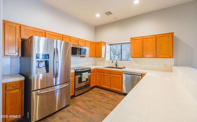 kitchen with dark hardwood / wood-style floors, sink, backsplash, tile counters, and stainless steel appliances