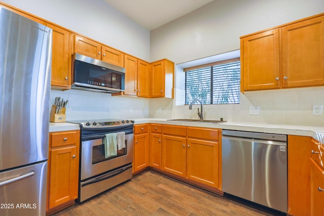 kitchen with appliances with stainless steel finishes, sink, backsplash, and dark hardwood / wood-style flooring