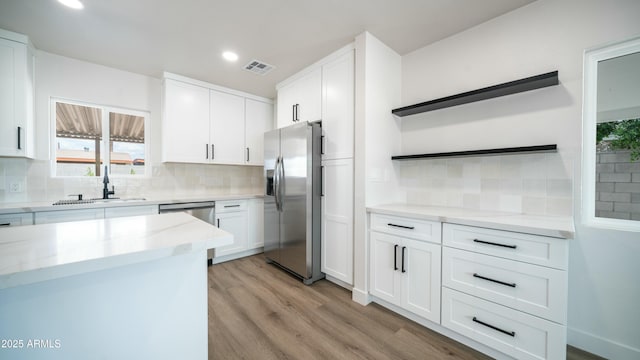 1838 E Earll Dr, Phoenix, AZ 85016 - kitchen with white cabinets, light wood-style flooring, visible vents, backsplash, and appliances with stainless steel finishes