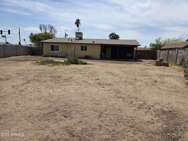 back of house featuring a fenced backyard and stucco siding