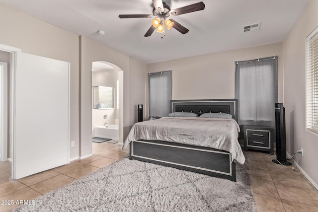 bedroom featuring light tile patterned floors, ceiling fan, and ensuite bathroom