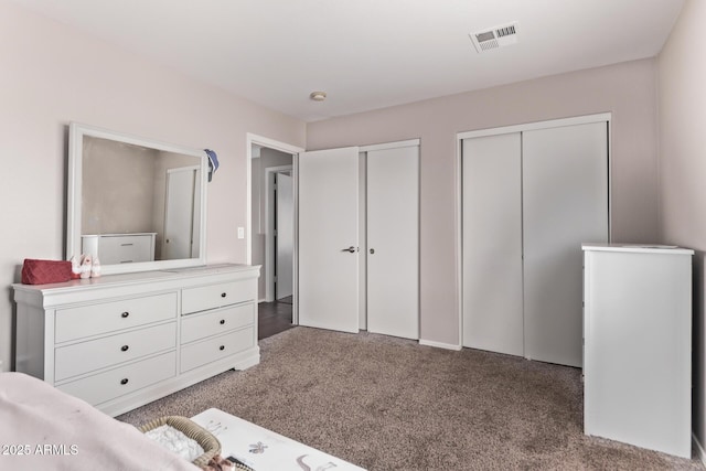 unfurnished bedroom featuring dark carpet and two closets