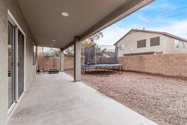 view of patio with a trampoline and an outdoor fire pit