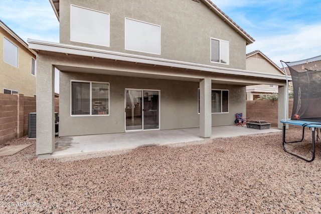 back of house with a trampoline, a patio, and an outdoor fire pit