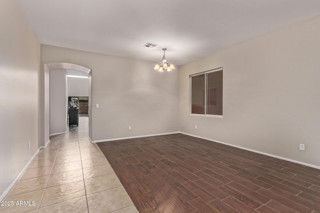 unfurnished room featuring an inviting chandelier and dark wood-type flooring