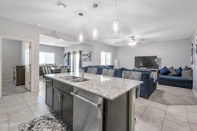 kitchen with light carpet, a healthy amount of sunlight, dishwasher, and an island with sink