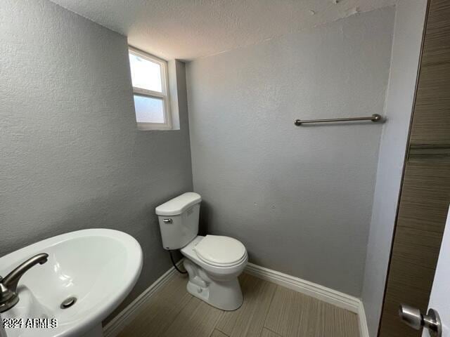 bathroom with hardwood / wood-style floors, toilet, sink, and a textured ceiling