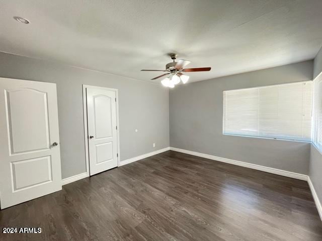 empty room with a wealth of natural light, ceiling fan, and dark hardwood / wood-style flooring