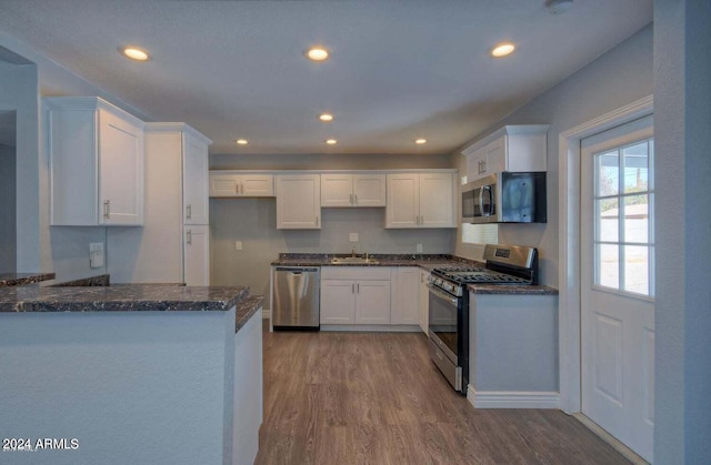 kitchen with appliances with stainless steel finishes, hardwood / wood-style floors, and white cabinets