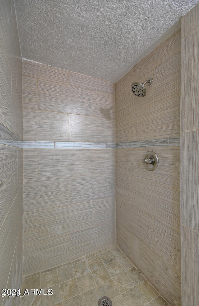 bathroom featuring a textured ceiling and a tile shower