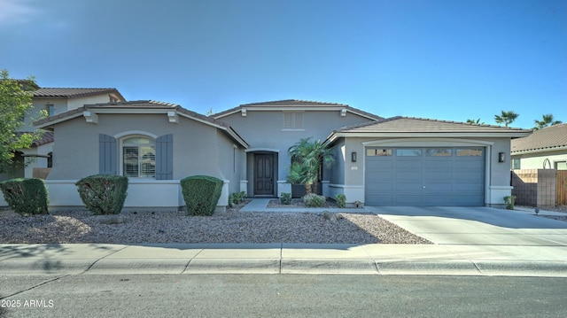 view of front facade featuring stucco siding, driveway, a tile roof, and a garage