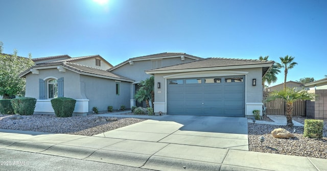 view of front of property featuring a tiled roof, a garage, driveway, and stucco siding