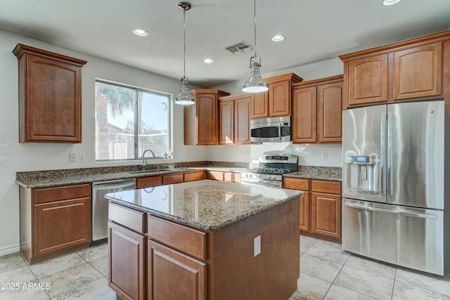 kitchen featuring sink, stone counters, appliances with stainless steel finishes, hanging light fixtures, and a center island