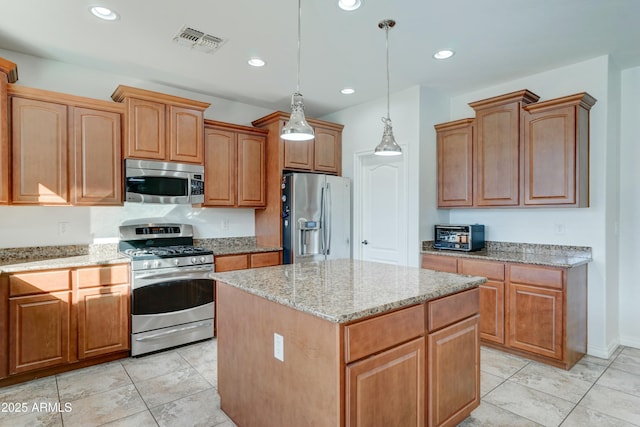 kitchen with light stone counters, appliances with stainless steel finishes, hanging light fixtures, and a kitchen island