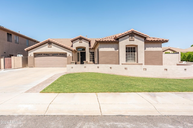 mediterranean / spanish-style house featuring an attached garage, a front lawn, a tiled roof, stucco siding, and driveway