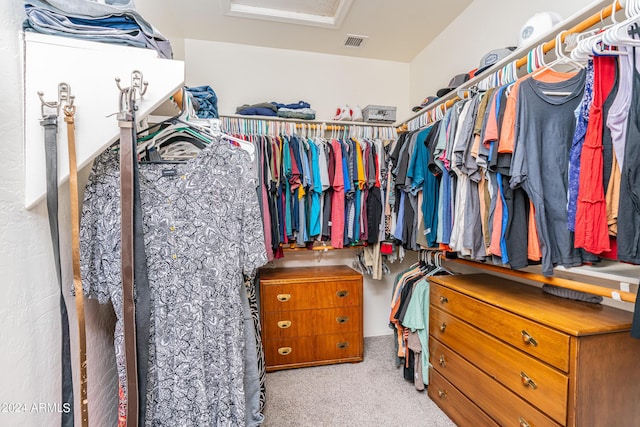 walk in closet with visible vents, attic access, and carpet floors