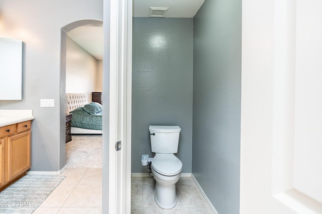 ensuite bathroom with vanity, toilet, tile patterned flooring, and connected bathroom