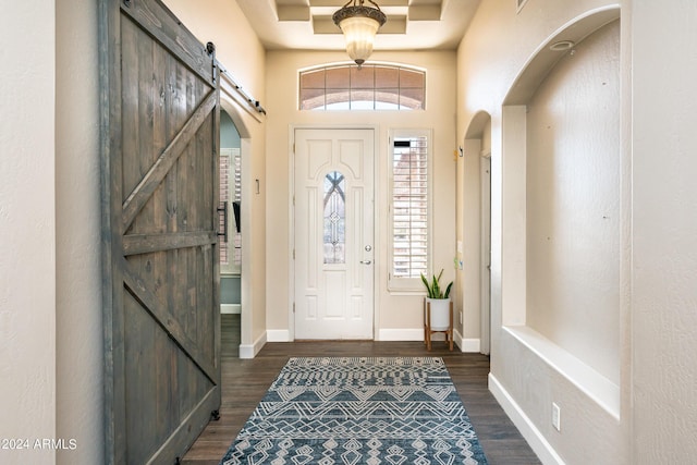 entrance foyer featuring dark wood finished floors, a barn door, arched walkways, and baseboards