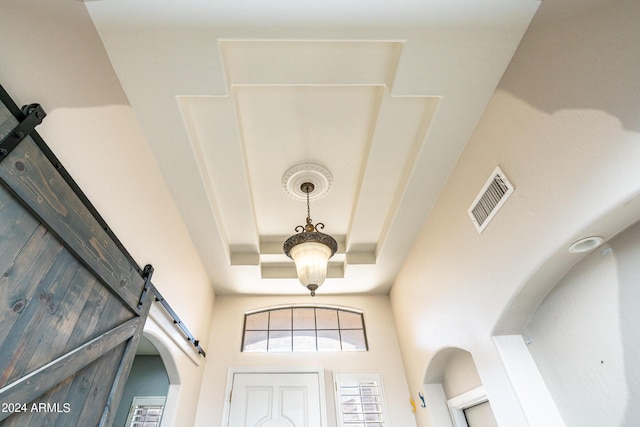 room details with a tray ceiling, visible vents, and a barn door