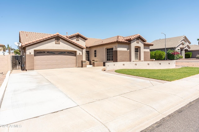 mediterranean / spanish house with a tiled roof, a garage, driveway, and stucco siding