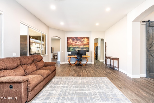 living room with baseboards, a barn door, recessed lighting, wood finished floors, and arched walkways