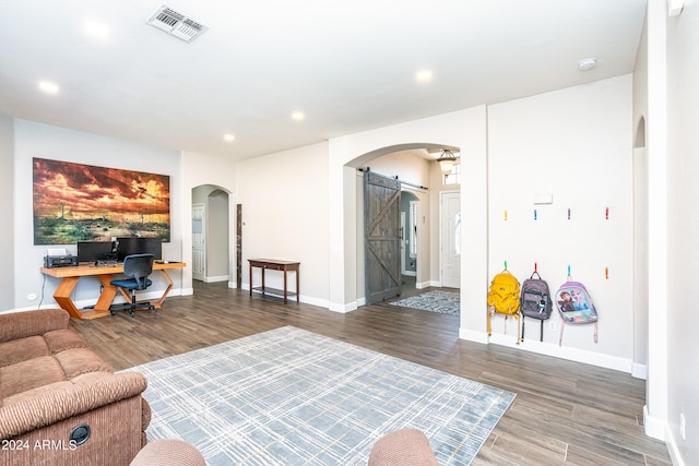 living room with visible vents, arched walkways, wood finished floors, and a barn door