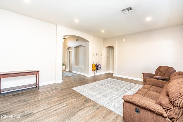 living room featuring visible vents, baseboards, recessed lighting, wood finished floors, and arched walkways